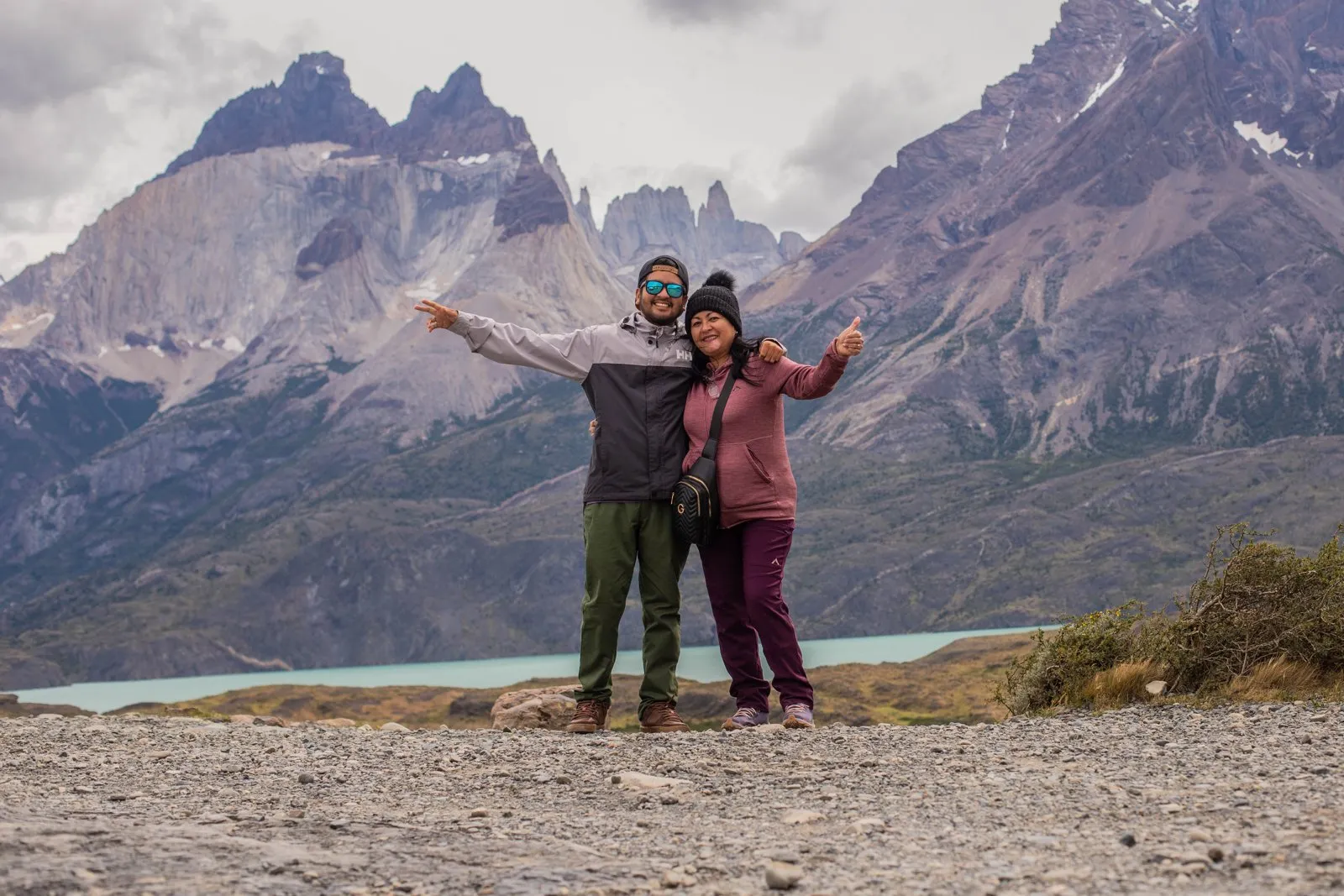 Travelers at a viewpoint facing the Cuernos del Paine and a turquoise lake