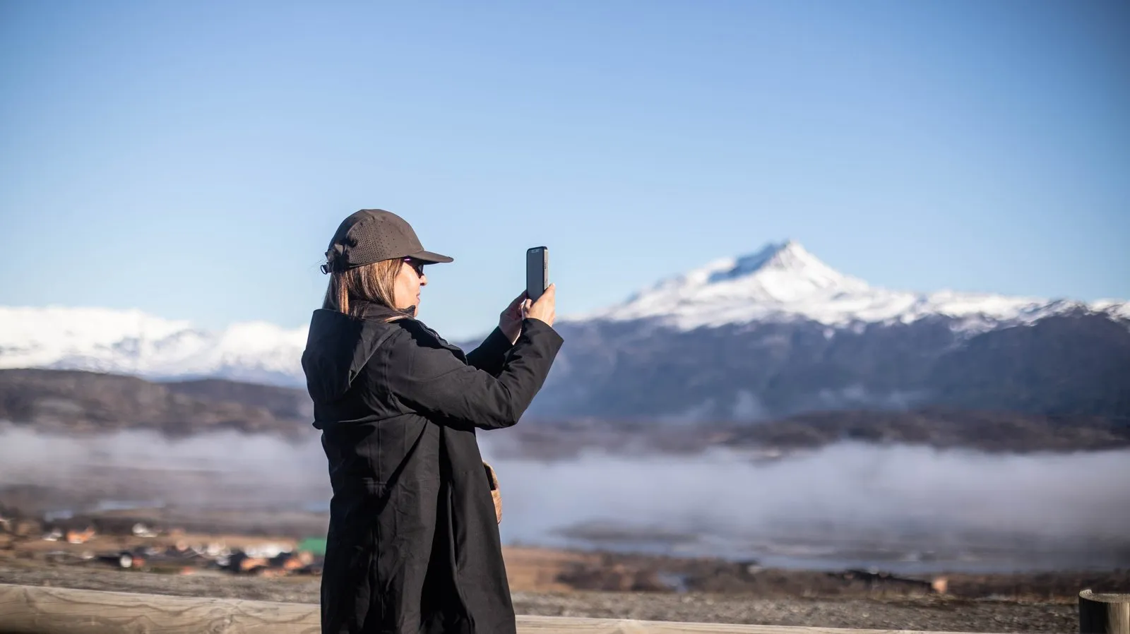 Traveler photographing snowy mountains in Torres del Paine